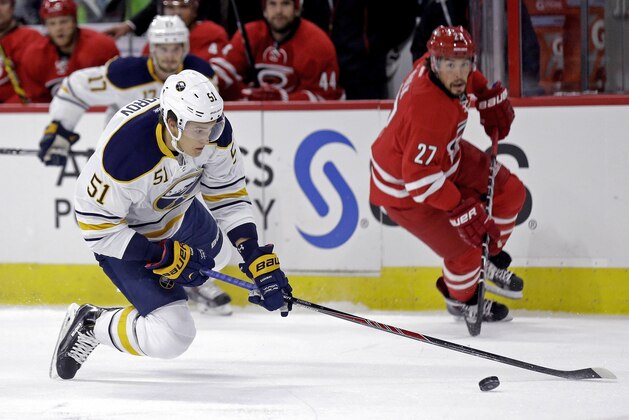 Buffalo Sabres' Nikita Zadorov (51) chases the puck as Carolina Hurricanes' Justin Faulk (27) watches during the first period of a preseason NHL hockey game in Raleigh, N.C., Friday, Oct. 3, 2014. (AP Photo/Gerry Broome)