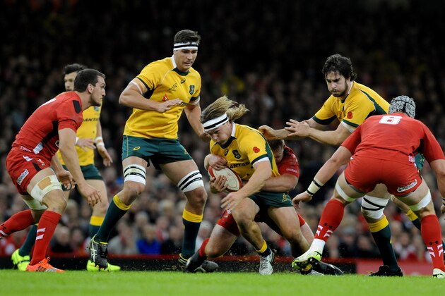 Australia's captain Michael Hooper, center, is tackled by Wales' Samson Lee during the international rugby union match between Wales and Australia at the Millennium Stadium, Cardiff, Wales, Saturday, Nov. 8, 2014. (AP Photo/Rui Vieira)