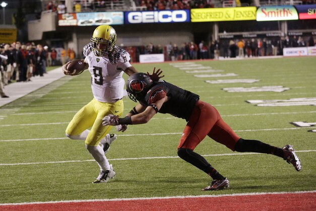 Oregon quarterback Marcus Mariota (8) scores a touchdown against Utah defensive back Brian Blechen (4) in the second half during an NCAA college football game Saturday, Nov. 8, 2014, in Salt Lake City. Oregon won 51-27. (AP Photo/Rick Bowmer)