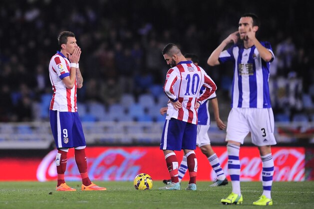 Atletico de Madrid's Mario Mandzukic of Croatia, left, laments beside Arda Turan of Turkey, center, after the second goal scored by Real Sociedad during their La Liga soccer match, at Anoeta stadium in San Sebastian, northern Spain, Sunday Nov. 9, 2014.  Atletico de madridlost 2-1.(AP Photo/Alvaro Barrientos)