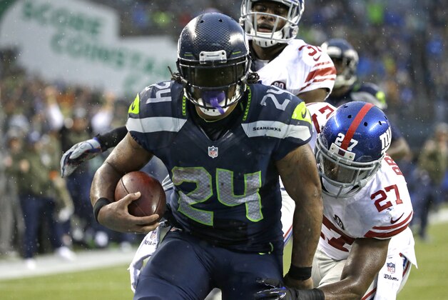 Seattle Seahawks running back Marshawn Lynch (24) scores his fourth touchdown of the NFL football game against the New York Giants, as Giants' Stevie Brown (27) attempts the tackle in the second half, Sunday, Nov. 9, 2014, in Seattle. (AP Photo/Elaine Thompson)