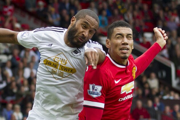 Manchester United's Chris Smalling, right, fights for the ball against Swansea City's Ashley Williams during their English Premier League soccer match at Old Trafford Stadium, Manchester, England, Saturday Aug. 16, 2014. (AP Photo/Jon Super)