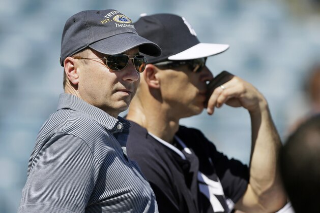 New York Yankees general manager Brian Cashman, left, and manager Joe Girardi sit behind the batting cage during spring training baseball practice Thursday, Feb. 20, 2014, in Tampa, Fla. (AP Photo/Charlie Neibergall)