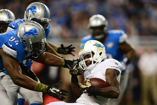 Nov 9, 2014; Detroit, MI, USA; Miami Dolphins wide receiver Jarvis Landry (14) is tackled by Detroit Lions defensive end Ezekiel Ansah (94) during the second quarter at Ford Field. Mandatory Credit: Andrew Weber-USA TODAY Sports
