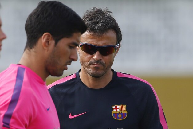 Barcelona head coach Luis Enrique, right, walks next to Luis Suarez, center, from Uruguay, during a training session at the Sports Center FC Barcelona Joan Gamper in San Joan Despi, in Barcelona, Spain, Friday, Aug. 15, 2014. Suarez trained with his Barcelona teammates on Friday after his ban for biting an opponent at the World Cup was softened but not shortened.The Court of Arbitration for Sport ruled Thursday that the Uruguay forward, who recently left Liverpool for Barcelona, deserves his four-month ban from playing official matches for both his club and his country. (AP Photo/Emilio Morenatti )