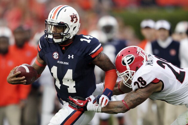Auburn quarterback Nick Marshall (14) runs out of the tackle of Georgia safety Tray Matthews (28) during the first half of an NCAA college football game in Auburn, Ala., Saturday, Nov. 16, 2013. (AP Photo/Jay Sailors)