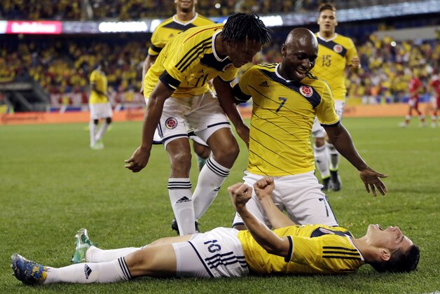 Colombia's James Rodriguez, bottom, celebrates with teammates Juan Caudrado, left, and Pablo Armero after scoring a goal against Canada during the second half of an international soccer friendly match, Tuesday, Oct. 14, 2014, in Harrison, N.J. (AP Photo/Julio Cortez)