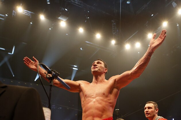 IBF, WBA, WBO and IBO champion Wladimir Klitschko from Ukraine is watched by his brother Vitali, right, as he celebrates winning the heavyweight world title bout against his Australian challenger Alex Leapai in Oberhausen, western Germany, Saturday, April 26, 2014. (AP Photo/Frank Augstein)