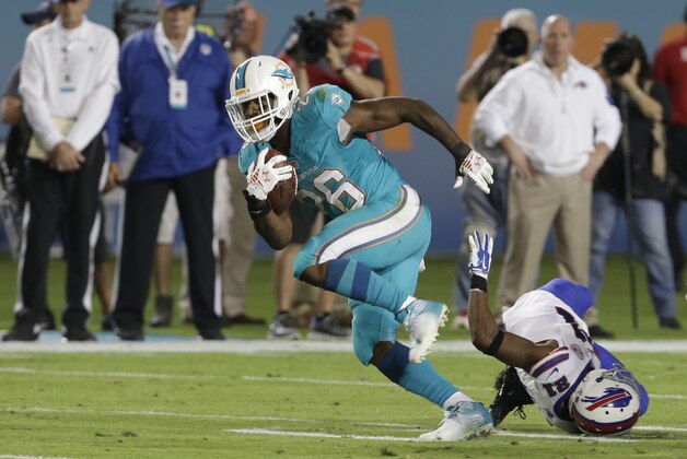 Miami Dolphins running back Lamar Miller (26) runs for yardage past Buffalo Bills cornerback Leodis McKelvin (21) during the first half of an NFL football game, Thursday, Nov. 13, 2014 in Miami Gardens, Fla. (AP Photo/Lynne Sladky)