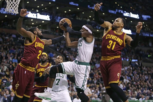 Boston Celtics guard Rajon Rondo, center, threads between Cleveland Cavaliers forward Shawn Marion (31) and guard Kyrie Irving (2) on a drive to the basket during the first quarter of an NBA basketball game in Boston, Friday, Nov. 14, 2014. (AP Photo/Charles Krupa)