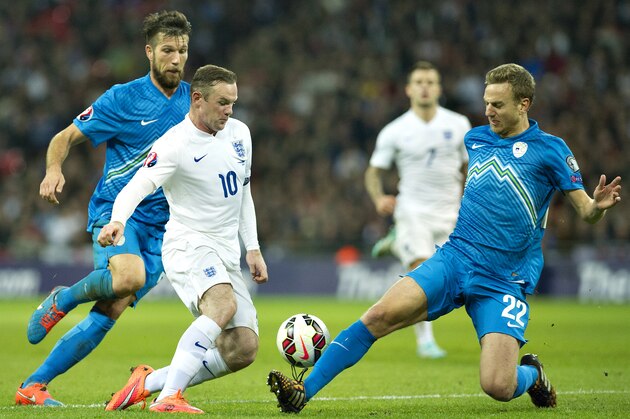 England's Wayne Rooney, center, controls the ball in front of Slovenia's Boston Cesar, left, and Ales Mertelj, during their Euro 2016 Group E qualifying soccer match at Wembley Stadium, London, Saturday, Nov. 15, 2014 (AP Photo/Bogdan Maran)
