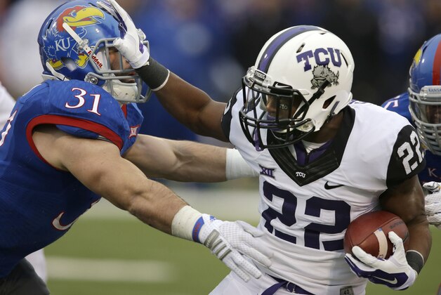 TCU running back Aaron Green (22) stiff arms Kansas linebacker Ben Heeney (31) during the first half of an NCAA college football game in Lawrence, Kan., Saturday, Nov. 15, 2014. (AP Photo/Orlin Wagner)