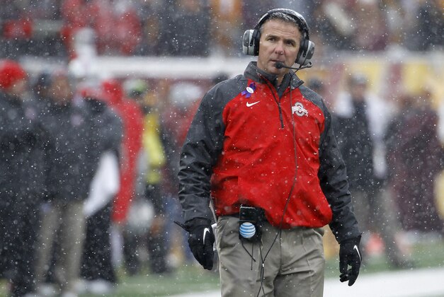 Ohio State head coach Urban Meyer walks out to his players in a timeout as snow falls during the fourth quarter of an NCAA college football game against Minnesota in Minneapolis Saturday, Nov. 15, 2014. Ohio State won 31-24. (AP Photo/Ann Heisenfelt)