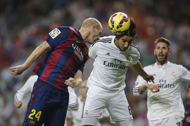 Real Madrid's Sami Khedira, centre, in action with Barcelona’s Jeremy Mathieu, left, during a Spanish La Liga soccer match between Real Madrid and FC Barcelona at the Santiago Bernabeu stadium in Madrid, Spain, Saturday, Oct. 25, 2014. (AP Photo/Andres Kudacki)