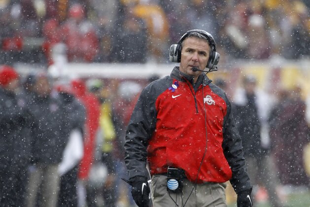 Ohio State head coach Urban Meyer walks out to his players in a timeout as snow falls during the fourth quarter of an NCAA college football game against Minnesota in Minneapolis Saturday, Nov. 15, 2014. Ohio State won 31-24. (AP Photo/Ann Heisenfelt)
