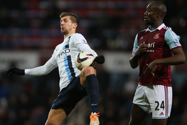West Ham's Carlton Cole, right, looks on as Manchester City's Matija Nastasic controls the ball during the second leg of the English League Cup semifinal soccer match between West Ham United and Manchester City in London, Tuesday, Jan. 21, 2014. (AP Photo/Alastair Grant)