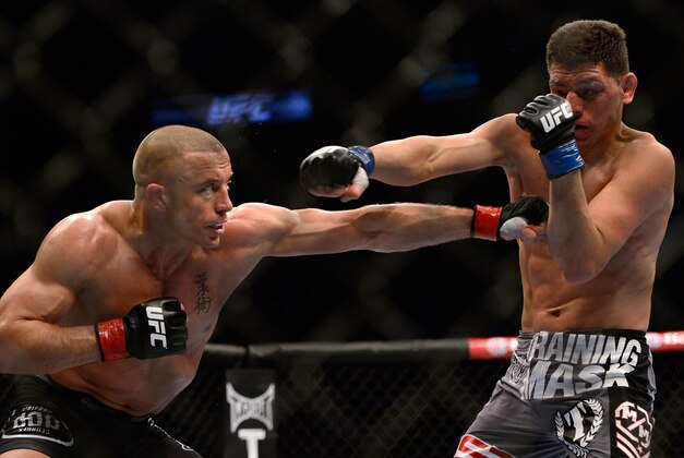 Mar 16, 2013; Montreal, Quebec, CAN;  Georges St.Pierre (red) and Nick Diaz (blue) throw simultaneous punches during their Welterweight title bout at UFC 158 at the Bell Centre. Mandatory Credit: Eric Bolte-USA TODAY Sports