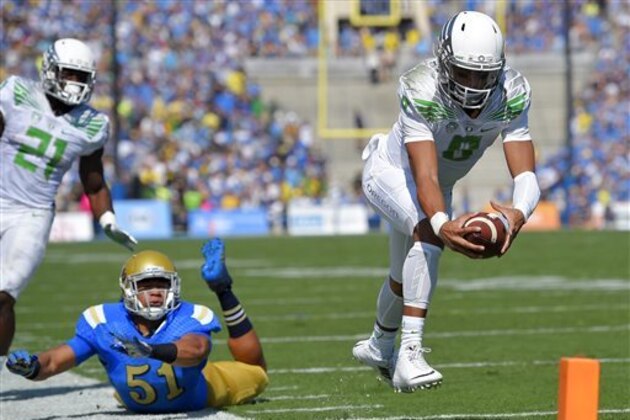 Oregon quarterback Marcus Mariota, right, dives in for a touchdown as UCLA linebacker Aaron Wallace, center, misses the tackle and running back Royce Freeman looks on during the first half of a NCAA college football game, Saturday, Oct. 11, 2014, in Pasadena, Calif. (AP Photo/Mark J. Terrill)
