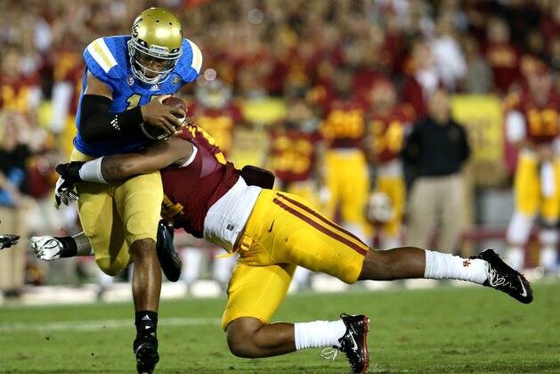 LOS ANGELES, CA - NOVEMBER 30:  Quarterback Brett Hundley #17 of the UCLA Bruins carries the ball as he is tackled by defensive end Leonard Williams #94 of the USC Trojans at Los Angeles Coliseum on November 30, 2013 in Los Angeles, California.  (Photo by Stephen Dunn/Getty Images)