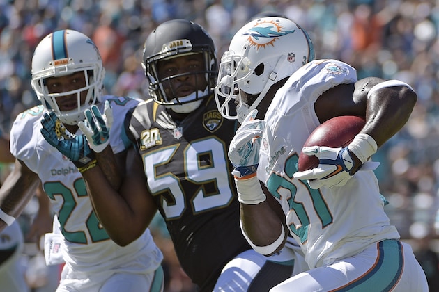 Miami Dolphins free safety Michael Thomas, right, runs back a blocked field goal-attempt past Jacksonville Jaguars defensive end Ryan Davis (59) during the first half of an NFL football game in Jacksonville, Fla., Sunday, Oct. 26, 2014. (AP Photo/Phelan M. Ebenhack)