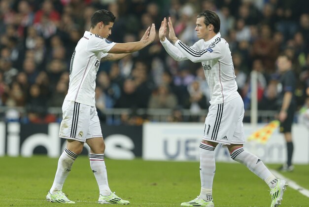 Real Madrid's James Rodriguez, left, is substituted for Real Madrid's Gareth Bale during a Group B Champions League soccer match between Real Madrid and Liverpool at the Santiago Bernabeu stadium in Madrid, Spain, Tuesday Nov. 4, 2014. (AP Photo/Paul White)