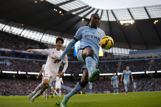 Manchester City's Yaya Toure, centre, keeps the ball from Swansea's Ki Sung-Yeung, left, during the English Premier League soccer match between Manchester City and Swansea at the Etihad Stadium, Manchester, England, Saturday Nov. 22, 2014. (AP Photo/Jon Super)
