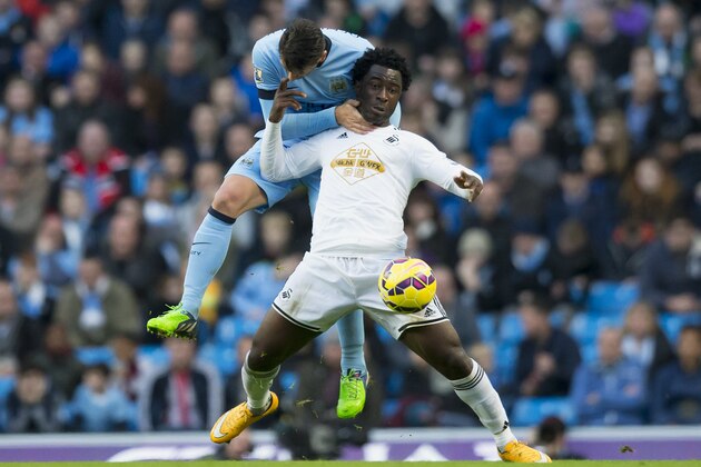 Manchester City's Martin Demichelis, left, gets a hold of Swansea's Wilfried Bony during the English Premier League soccer match between Manchester City and Swansea at the Etihad Stadium, Manchester, England, Saturday Nov. 22, 2014. (AP Photo/Jon Super)