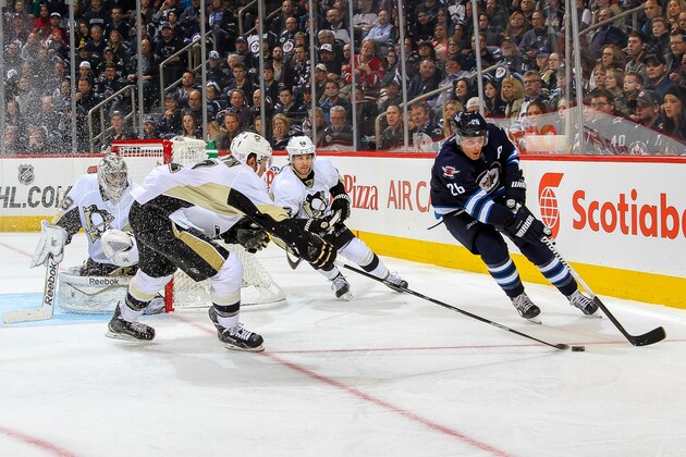 WINNIPEG, CANADA - NOVEMBER 6: Blake Wheeler #26 of the Winnipeg Jets plays the puck around the net as Paul Martin #7 and Kris Letang #58 of the Pittsburgh Penguins defend during third period action on November 6, 2014 at the MTS Centre in Winnipeg, Manitoba, Canada. The Pens defeated the Jets 4-3 in the shootout. (Photo by Jonathan Kozub/NHLI via Getty Images)