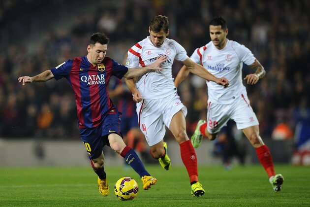 FC Barcelona's Lionel Messi, left, duels for the ball against Sevilla's Grzegorz Krychowiak, center, during a Spanish La Liga soccer match at the Camp Nou stadium in Barcelona, Spain, Saturday, Nov. 22, 2014. (AP Photo/Manu Fernandez)