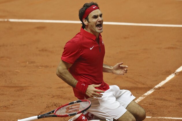 Switzerland's Roger Federer falls to the clay after defeating France's Richard Gasquet and winning the Davis Cup final between France and Switzerland at Stade Pierre Mauroy in Lille, northern France, Sunday, Nov. 23, 2014. (AP Photo/Peter Dejong)
