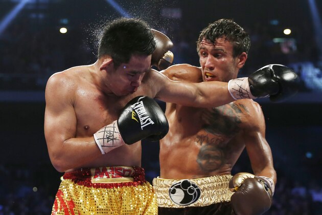 Chonlatarn Piriyapinyo, left, of Thailand gets a punch from Vasyl Lomachenko of Ukraine during their WBO world featherweight boxing title match at the Venetian Macao in Macau, Sunday, Nov. 23, 2014. (AP Photo/Kin Cheung)