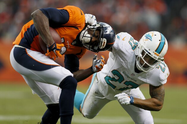 Denver Broncos wide receiver Emmanuel Sanders, left, is brought down by Miami Dolphins strong safety Jimmy Wilson (27) during the first half of an NFL football game, Sunday, Nov. 23, 2014, in Denver. (AP Photo/Joe Mahoney)