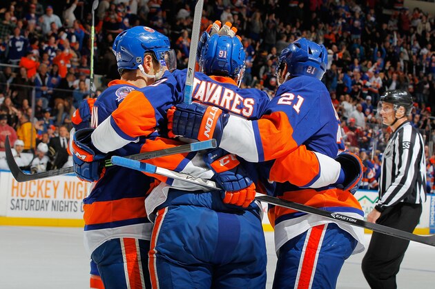 UNIONDALE, NY - NOVEMBER 22: John Tavares #91 of the New York Islanders is mobbed by teammates congratulating him on his third period goal during the game against the Pittsburgh Penguins on November 22, 2014 at Nassau Veterans Memorial Coliseum in Uniondale, New York. The Islanders defeated the Penguins 4-1. (Photo by Jim McIsaac/NHLI via Getty Images)