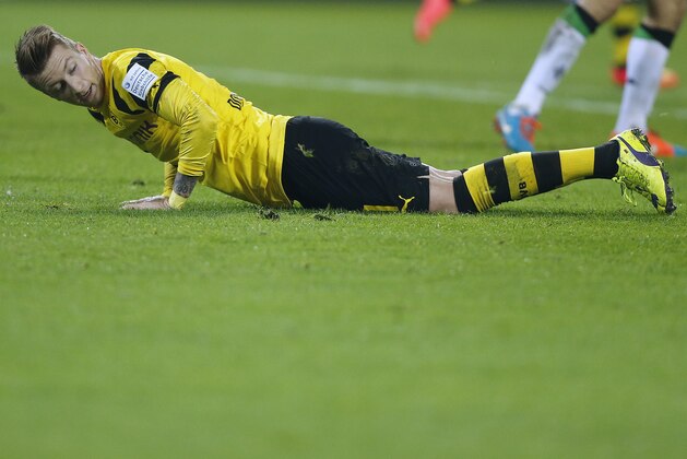 Dortmund's Marco Reus lies on the pitch  during the German first division Bundesliga soccer match between BvB Borussia Dortmund and VfL Borussia Moenchengladbach in Dortmund, Germany, Sunday, Nov. 9, 2014. (AP Photo/Frank Augstein)
