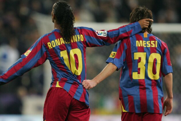 MADRID, SPAIN - NOVEMBER 19:  Ronaldinho (L) of  Barcelona celebrates with Lionel Messi after scoring a goal during the Primera Liga match between Real Madrid and F.C. Barcelona at the Bernabeu on November 19, 2005 in Madrid, Spain.  (Photo by Denis Doyle/Getty Images)