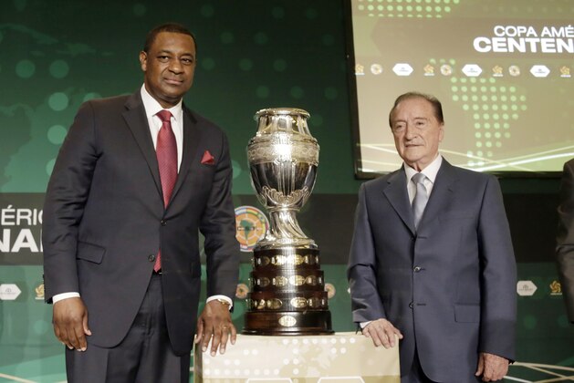 CONCACAF president Jeffrey Webb, left, and Eugenio Figueredo, right, president of CONMEBOL, the South American soccer confederation, pose for photographers next to the Copa America trophy during a news conference in Bal Harbour, Fla., Thursday, May 1, 2014. The United States will host the Copa America soccer tournament for the first time in 2016. The Copa America, the world's oldest intercontinental soccer tournament, will celebrate its 100th anniversary in 2016. (AP Photo/Alan Diaz)