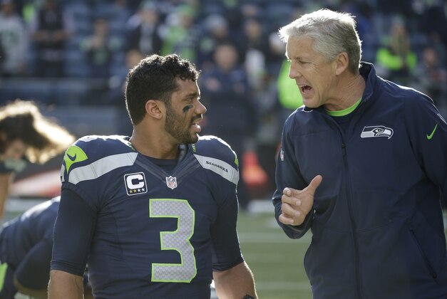Seattle Seahawks quarterback Russell Wilson, left, talks with head coach Pete Carroll, right, before an NFL football game against the Arizona Cardinals,  Sunday, Nov. 23, 2014, in Seattle. (AP Photo/Elaine Thompson)