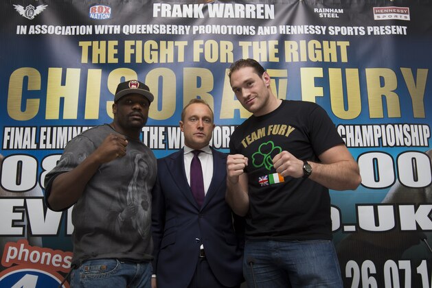 Boxers Dereck Chisora, left, and Tyson Fury stand either side of Francis Warren, son of promoter Frank Warren at a press conference to publicise their forthcoming world title eliminator fight, Manchester, England, Thursday March 20, 2014. The fight will take place on 26 July in Manchester with the winner possibly going on to challenge IBF, WBA and WBO heavyweight champion Wladimir Klitschko. (AP Photo/Jon Super)