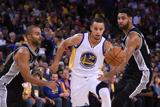 Nov 11, 2014; Oakland, CA, USA; Golden State Warriors guard Stephen Curry (30) dribbles the basketball against San Antonio Spurs guard Tony Parker (9, left) and forward Tim Duncan (21, right) during the first quarter at Oracle Arena. The Spurs defeated the Warriors 113-100. Mandatory Credit: Kyle Terada-USA TODAY Sports
