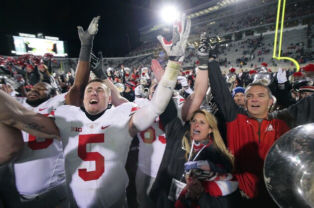 FILE - In this Nov. 9, 2014, file photo, Ohio State's Jeff Heuerman (5), coach Urban Meyer, right, and Meyer's wife, Shelley, celebrate following the team's 49-37 win over Michigan State in an NCAA college football game in East Lansing, Mich. Every year except one from 1935-2012, the Ohio State Buckeyes were able to focus entirely on their annual season-ending rivalry with Michigan. But now, for the second year in a row, not only do they have the Wolverines to deal with but also the Big Ten title game looming a week later. (AP Photo/Al Goldis, File)