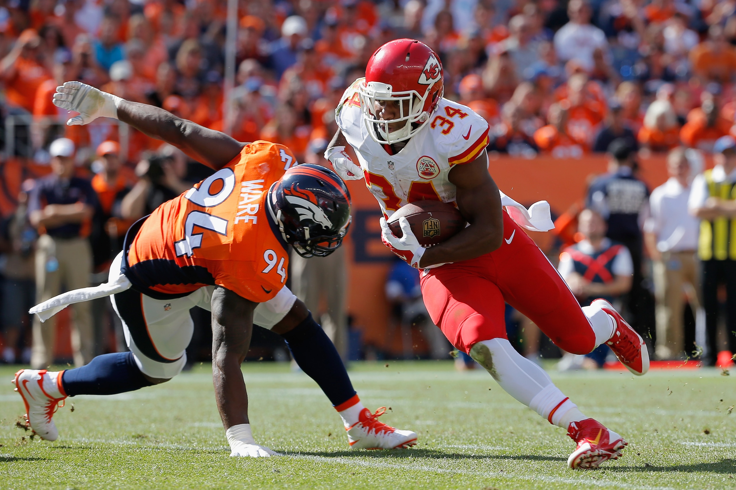 DENVER, CO - SEPTEMBER 14:  Running back Knile Davis #34 of the Kansas City Chiefs carries the ball against defensive end DeMarcus Ware #94 of the Denver Broncos at Sports Authority Field at Mile High on September 14, 2014 in Denver, Colorado. The Broncos defeated the Chiefs 24-17.  (Photo by Doug Pensinger/Getty Images)