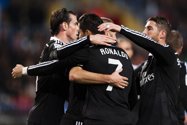 Real Madrid's Karim Benzema from France, center, is surrounded by teammates to celebrate his goal during a Spanish La Liga soccer match between Malaga and Real Madrid at La Rosaleda stadium in Malaga, Spain, Saturday Nov. 29, 2014. (AP Photo/Daniel Tejedor)