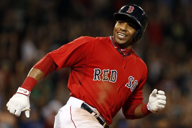Boston Red Sox's Yoenis Cespedes smiles at teammates charging out of the dugout after hitting the game-winning RBI single against the Toronto Blue Jays during the 10th inning of the Red Sox's 9-8 win in a baseball game at Fenway Park in Boston on Friday, Sept. 5, 2014. (AP Photo/Winslow Townson)