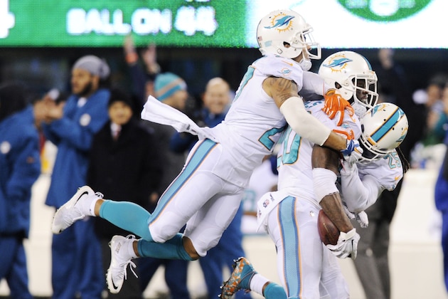 Miami Dolphins strong safety Reshad Jones (20) is mobbed by strong safety Jimmy Wilson (27) and free safety Louis Delmas (25) after intercepting a pass by the New York Jets with seconds left in the fourth quarter of an NFL football game, Monday, Dec. 1, 2014, in East Rutherford, N.J. The Dolphins won 16-13. (AP Photo/Bill Kostroun)
