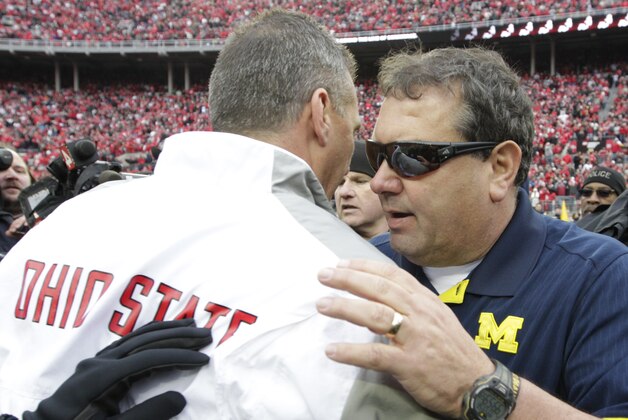 Michigan head coach Brady Hoke, right, shakes hands with Ohio State head coach Urban Meyer after Ohio State beat Michigan in an NCAA college football game Saturday, Nov. 29, 2014, in Columbus, Ohio. Ohio State beat Michigan 42-28. (AP Photo/Jay LaPrete)