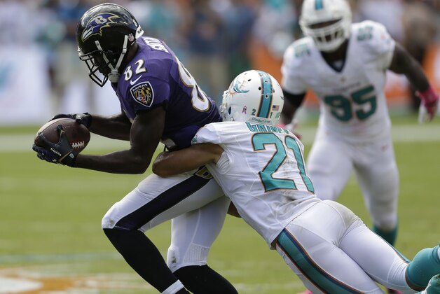 Miami Dolphins cornerback Brent Grimes (21) tackles Baltimore Ravens wide receiver Torrey Smith (82) during the second half of an NFL football game, Sunday, Oct. 6, 2013, in Miami Gardens, Fla. (AP Photo/Wilfredo Lee)