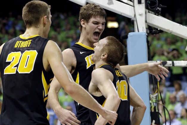 Iowa's Jarrod Uthoff (20), Adam Woodbury and Mike Gesell (10) celebrate towards the end of Iowa's 60-55 win over North Carolina during the second half of an NCAA college basketball game in Chapel Hill, N.C., Wednesday, Dec. 3, 2014. (AP Photo/Gerry Broome)
