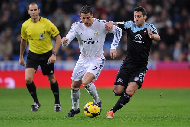 MADRID, SPAIN - JANUARY 06:  Cristiano Ronaldo (C) of Real Madrid CF battles for the ball against Hugo Mallo (R) of RC Celta de Vigo while referee Alfonso Alvarez looks on during the La Liga match between Real Madrid CF and RC Celta de Vigo at the Santiago Bernabeu stadium on January 6, 2014 in Madrid, Spain.  (Photo by Denis Doyle/Getty Images)