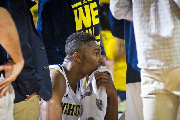 Michigan guard Zak Irvin (21) sits in a huddle with teammates during a timeout in the second half of an NCAA college basketball game against N.J.I.T. at Crisler Center in Ann Arbor, Mich., Saturday, Dec. 6, 2014. N.J.I.T. won 72-70. (AP Photo/Tony Ding)