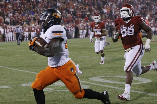 Oklahoma defensive tackle Chuka Ndulue (98) chases as Oklahoma State wide receiver Tyreek Hill, left, runs a punt return 91 yards for a touchdown in the fourth quarter of an NCAA college football game, tying the score and setting up an overtime, in Norman, Okla., Saturday, Dec. 6, 2014. Oklahoma State won 38-35 in overtime. (AP Photo/Sue Ogrocki)